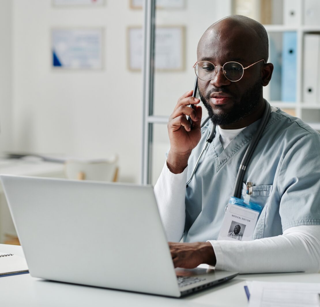 Doctor at laptop on phone